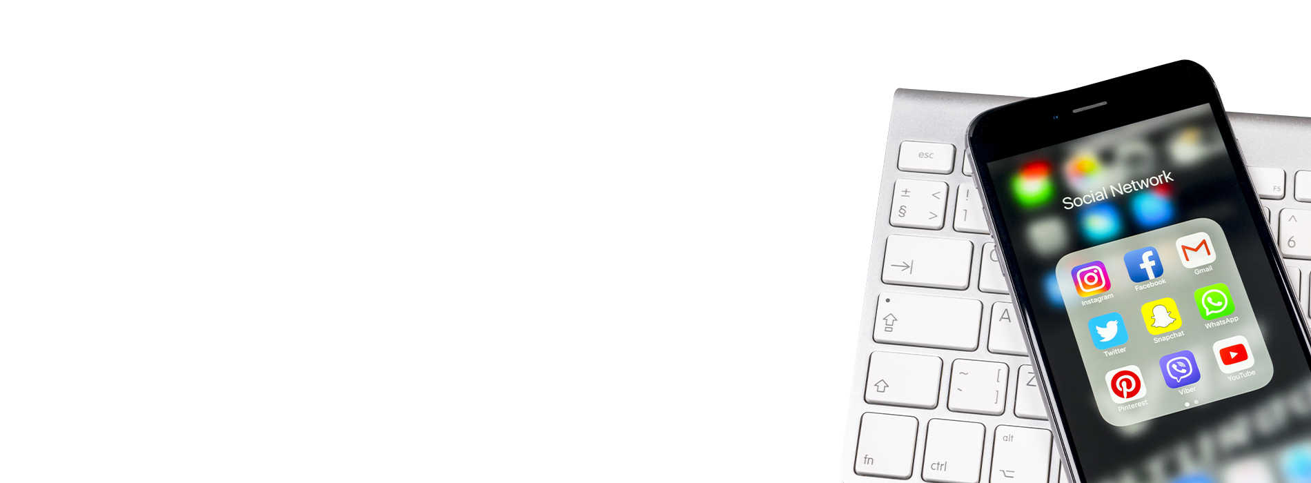 The image shows a smartphone placed on top of a computer keyboard, with both devices in focus against a blurred background.